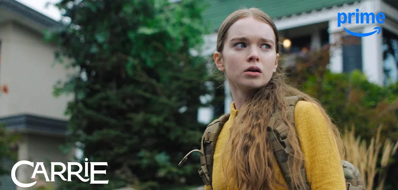 Summer H. Howell as Carrie White in a yellow cardigan with a backpack, outside a house, in a still from the official Carrie trailer